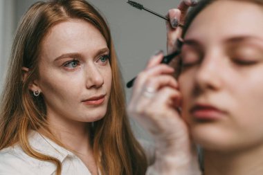 Beyaz tenli stajyerin kaş tedavisiyle ilgilenen danışman. Odaklanma eğitimi ve klinik sakinliğiyle.