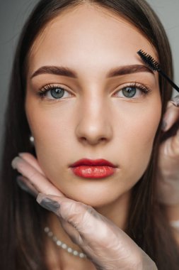 Stüdyo portre modeli maskara ve ruj sürmüş bitmiş kaşları, pürüzsüz cildi ve yumuşak rengini gösteriyor.