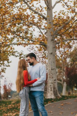 Aşıklar doğanın içinde şefkatli bir anı paylaşıyorlar, samimi çiftler sonbahar ağaçlarının gölgesinde birbirlerine bakıyorlar.