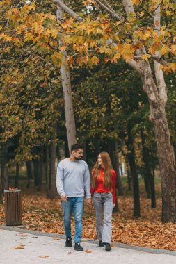 Sonbaharda ağaçların arasında yürüyen çift ayak altında düşen yapraklar, gündelik giysiler ve rahat bir hayat sürüyor.