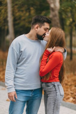 Eğlenceli sonbahar sokak gezintisi. Beyaz çift yaprak kaplı yolda birbirlerini tutuyorlar. Sıradan kot ve yumuşak kot.