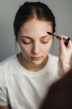 Esmer, beyaz tenli bir müşteri yumuşak fırça, kapalı gözler, sakin bir ifade, nazik bir karışım sergiliyor.