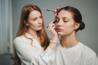 Esmer beyaz tenli eğitmen öğrencilere kaş stili teknikleri öğretiyor. Elleri gösteride, stüdyo rehberliği atmosferinde.,
