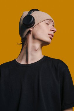 Kulaklık takan genç bir adamın yan profili, güçlü hatları ve minimalist ışıklandırması olan düşünceli editör portresi, model.