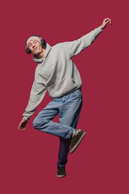 Kapüşonlu ve kulaklıklı genç adam kestane rengi zemine karşı Midair 'i yakaladı. Serbest Dansçı