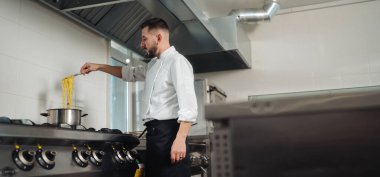 Şef taze makarnayı büyük haşlama tenceresine indiriyor, mükemmel doku için aşçı olarak buhar yükseliyor.