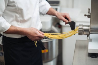 Şef, Extruder 'dan taze makarna ipliklerini çekiyor, Sanatsal Makarna Yapımı ve Hamur Dokusunu gösteriyor