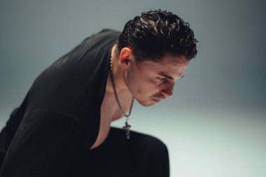 Kara kara düşünen meçhul ırk adamı. Çağdaş dans provası sırasında çapraz kolye, sade stüdyo ışıklandırması.,