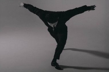 Stüdyo katının üstünde zıplayan erkek dansçı, yüksek gerilim, güçlü çizgi, askıya alınmış hareket, atletik form, dramatik gölge, canlı