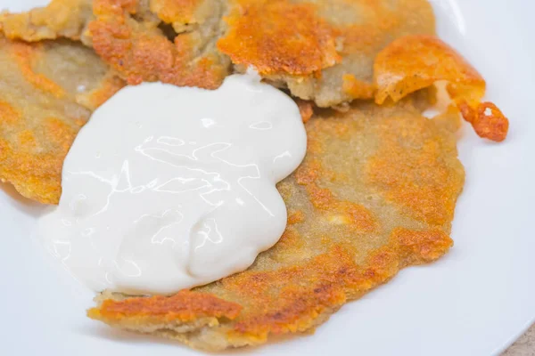 Potato pancakes with sour cream on ceramic white plate — Stock Photo, Image