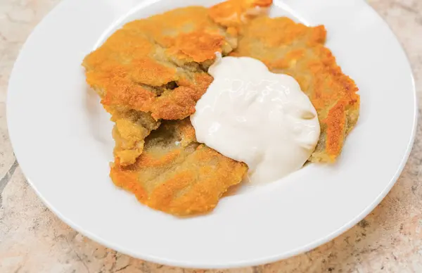 Potato pancakes with sour cream on ceramic white plate — Stock Photo, Image