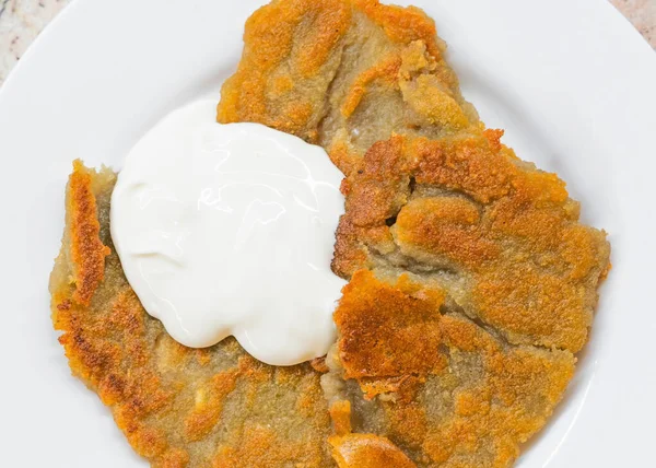 Potato pancakes with sour cream on ceramic white plate — Stock Photo, Image