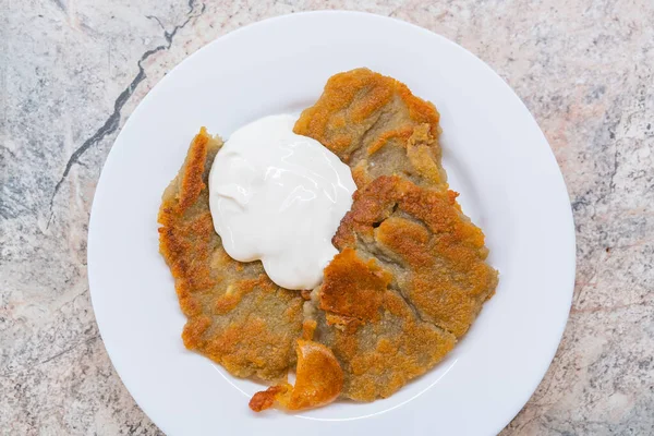 Potato pancakes with sour cream on ceramic white plate — Stock Photo, Image