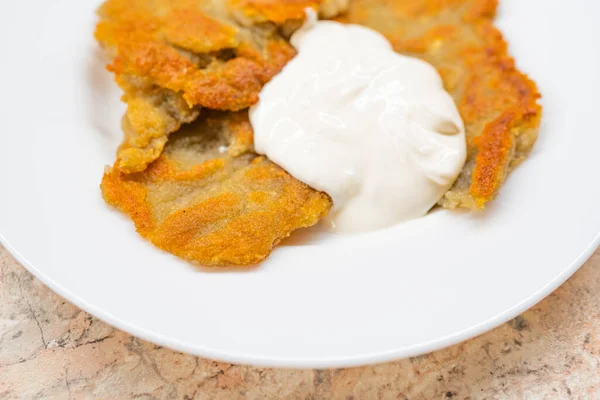 Potato pancakes with sour cream on ceramic white plate — Stock Photo, Image