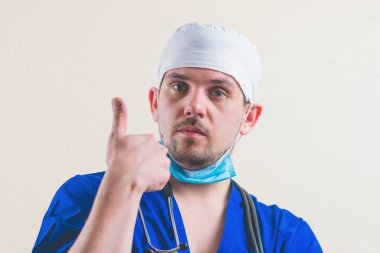 Mavi cerrah kıyafetiyle genç doktor portresi izole edilmiş.