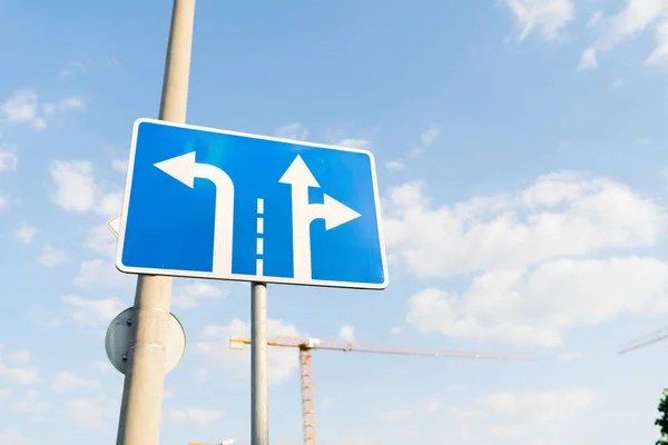 Arka planda mavi gökyüzü olan thetraffic şeritlerinde dönüş kurallarını gösteren mavi trafik işareti.