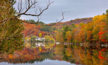Fall colours along the Gatineau river reflected in water, Wakefield, Quebec, Canada