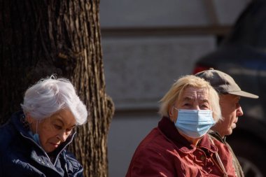 RIGA, LATVIA. 8 Ekim 2020. Seçici odak fotoğrafı. Otobüs durağında yüzü koruyan maske takan yaşlı bir kadın..
