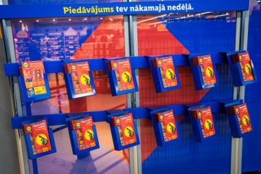 RIGA, LATVIA. 12 Mart 2026. Bir süpermarkette sergilenen basılı indirimli broşürler ve haftalık teklifler. Yeni LIDL mağaza açılışı.