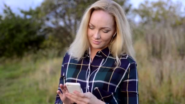 Jonge vrouw luisteren naar muziek op haar smartphone — Stockvideo