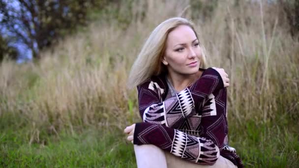 Ελκυστική νεαρή γυναίκα που κάθεται έξω και να προσπαθεί να κρατήσει ζεστό — Αρχείο Βίντεο