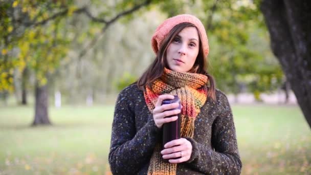 Belle jeune femme ouvre un thermotasse et boire du thé chaud dans le parc d'automne . — Video