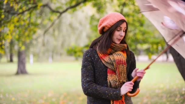 Schöne junge Frau öffnet Schirm und dreht ihn. Mädchen lächelt und blickt an einem regnerischen Herbsttag freudig in den klaren Himmel und schaut dann in die Kamera. — Stockvideo