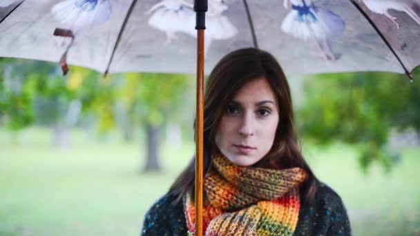 Hermosa joven mujer de pie con un paraguas en la lluvia . — Vídeos de Stock