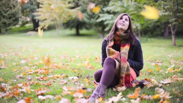 Mooie jonge vrouw zitten in de herfst park. Bladeren vallen rond meisje in Slow Motion. — Stockvideo