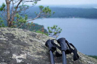 Kayanın tepesinde duran yürüyüş sopaları. Seyahat ve turizm kavramı