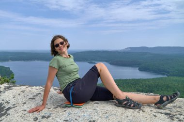 Kayanın tepesinde oturan mutlu kadın turist