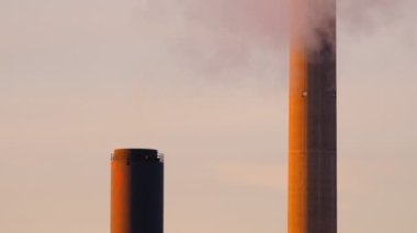 Sarı gün batımı ışığında dumanlı CHP bitki borularının yakın görüntüsü