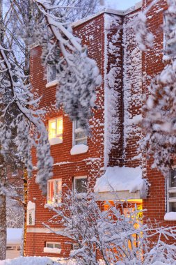 Finlandiya 'da şiddetli bir kar fırtınasından sonra konut binasının kar kaplı kırmızı tuğla duvarı.
