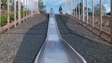 Mutlu kız Finlandiya 'da halka açık bir parkta kayıyor. Modern ahşap oyun alanı. Modern İskandinav mimarisi.