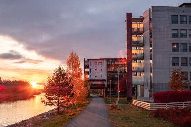 Finlandiya 'da altın sonbahar döneminde günbatımı arka planında modern apartman binası. Modern İskandinav mimarisi.