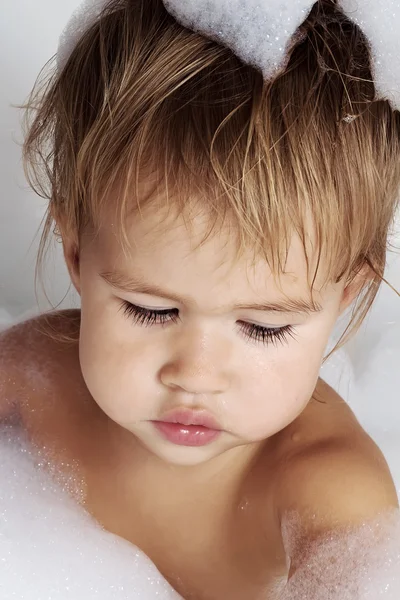 Little girl surrounded soap suds. — Stock Photo, Image