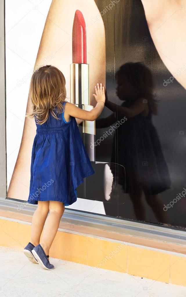 Little girl looking through shop window