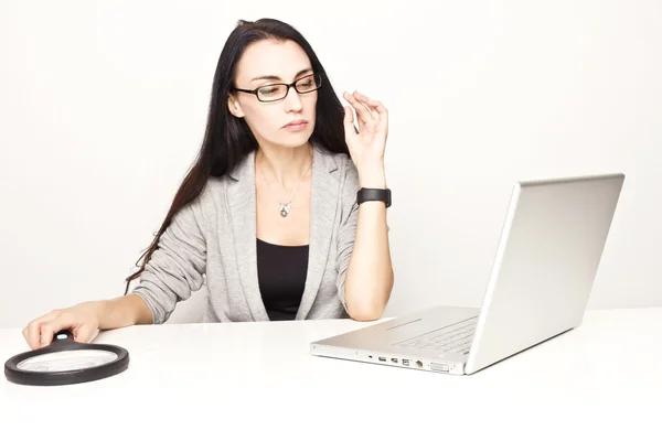 Mujer de negocios que comprueba el ordenador usando loupe . — Foto de Stock