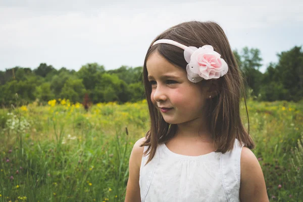 Innocent little girl outdoors in park with wild grass and flower — Stock Photo, Image