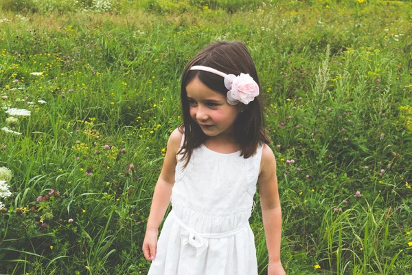 Innocent little girl in white dress outdoors in park with wild g — Stock Photo, Image