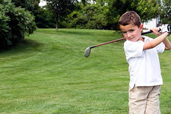 Kleine jongen golfer swingende een club op de golfbaan — Stockfoto