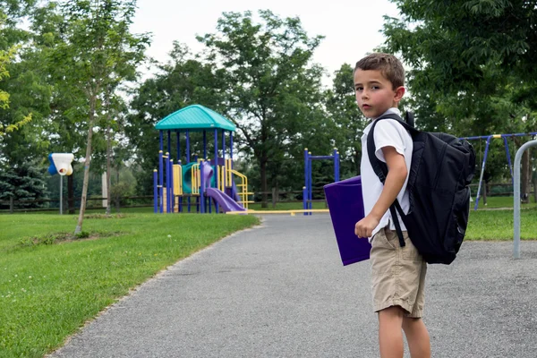 Child with school backpack and book walking in the park — Stock Photo, Image