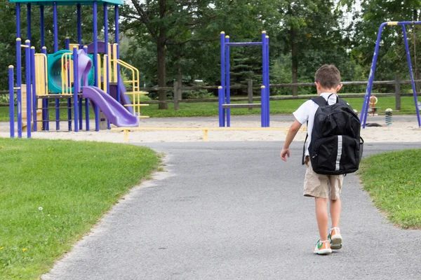 Kind met school rugzak en boek wandelen in het park — Stockfoto