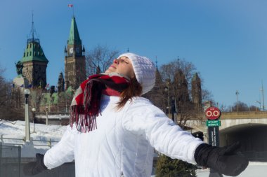 Young woman basks in the warm winter sun in front of Canada's Pa clipart