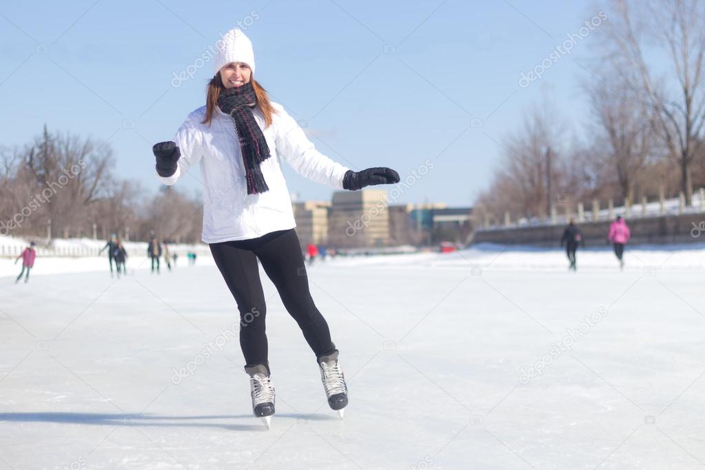 Attractive young woman ice skating during winter 