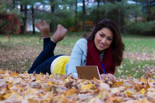 Stijlvolle vrouw schrijven in haar notitieblok buiten in de herfst — Stockfoto