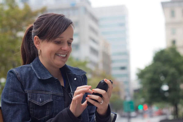 Γυναίκα γραπτών μηνυμάτων με το έξυπνο τηλέφωνο εκτός της πόλης — Φωτογραφία Αρχείου
