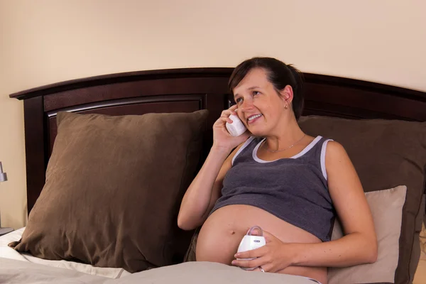 Беременная женщина играет с радионяней в своей спальне — стоковое фото