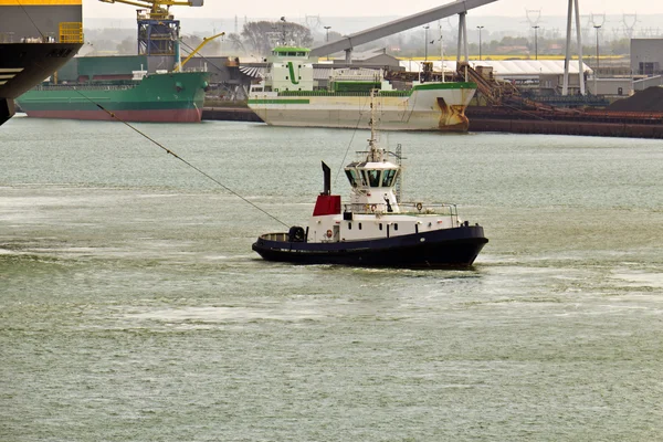 Tugboat towing ship in harbor — Stock Photo, Image