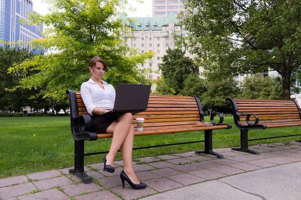 Donna d'affari sul banco del parco che lavora con il computer portatile — Foto Stock